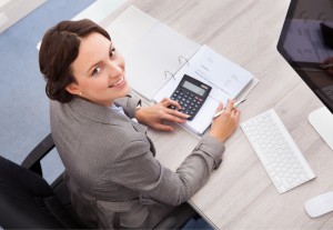 Portrait Of Smiling Young Female Accountant Calculating Bills
